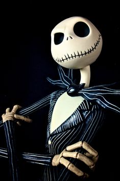 a skeleton dressed up in a suit and bow tie holding a cane with his right hand