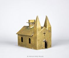 a small gold church with a top hat on it's roof and two windows