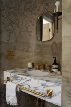 a bathroom with marble counter tops and gold fixtures, along with a mirror above the sink