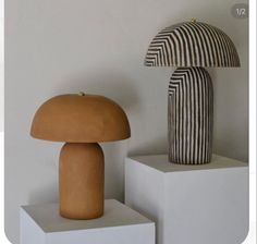 two mushroom sculptures on pedestals in front of a white wall