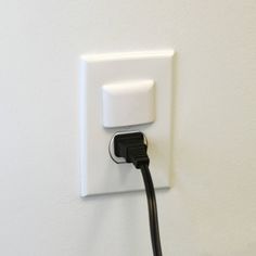 an electrical outlet plugged in to a white wall with a black cord running through it