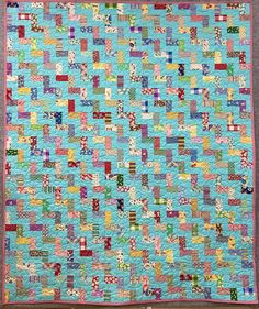 a blue quilt with many different colored squares on the top and bottom, along with pink trimmings