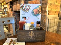 a wooden box with food on it sitting on a table next to a fork and napkin