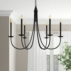 a black chandelier hanging from the ceiling in a room with white curtains and windows