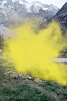 a yellow substance is spewing out from the ground in front of some mountains