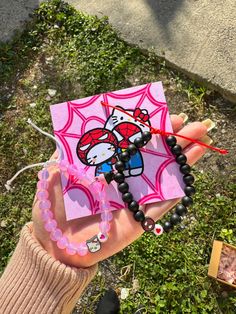 a person holding up a hello kitty card and beaded bracelet