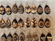 a collection of wooden earrings hanging on a wall next to each other with different designs