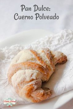 a croissant with powdered sugar on it laying on top of a white plate