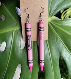 two pink crayons are hanging from earrings