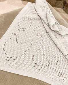 a white crocheted blanket laying on top of a bed next to a pillow