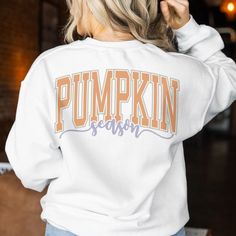 a woman with blonde hair wearing a white sweatshirt that says pumpkin season on the front