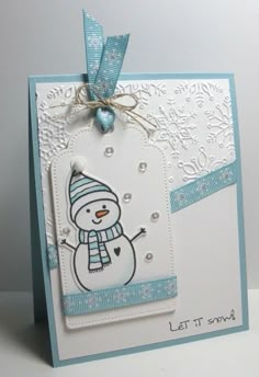 a card with a snowman on it and a blue ribbon around the edge that says let it snow