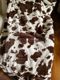 a brown and white cow print blanket sitting on top of a bed