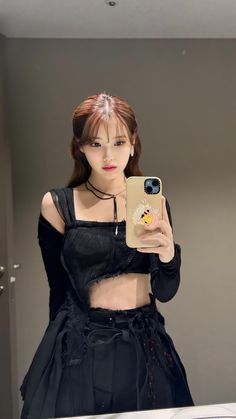 a woman taking a selfie in front of a mirror wearing a black top and skirt