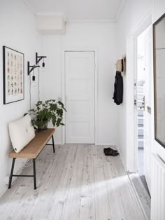 a white hallway with a bench and coat rack