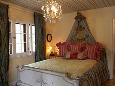 a bedroom with a fancy bed and chandelier