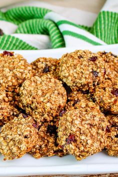 a white plate topped with oatmeal and raisins covered cookies next to a green napkin