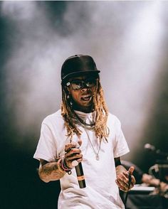 a man with dreadlocks holding a microphone and standing in front of a stage