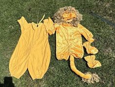 a stuffed animal is laying on the grass next to an unmade onesie suit