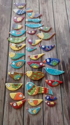 colorful wooden birds are arranged in a row on a wood floor, with eyes painted on them