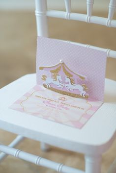 a pink princess birthday card sitting on top of a white chair with the word kara's party ideas pink carousel birthday