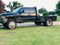 a black truck parked on top of a lush green field