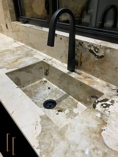 a bathroom sink with a black faucet and marble counter top in front of a mirror