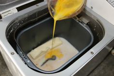 someone is pouring something into a washing machine and it's yellow liquid being poured on top