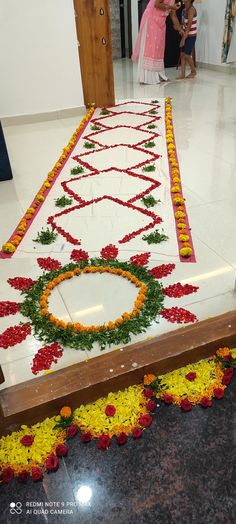 a long table with flowers on it and people standing in the background looking at it