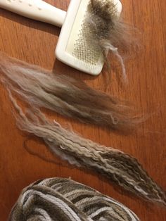 two skeins of yarn and a hair brush on a table