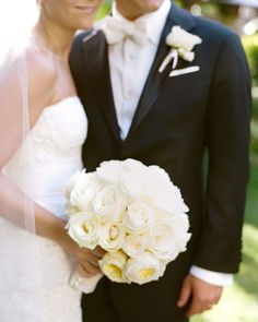 a bride and groom pose for a wedding photo in their tuxedo, black suit, and white bouquet