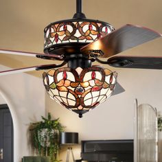 a ceiling fan with stained glass shades hanging from it's blades in a living room