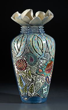 a blue vase with an intricate design on it's body and bottom, sitting on a black surface