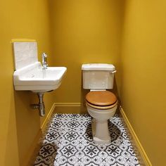 a white toilet sitting next to a sink in a bathroom under a window with yellow walls