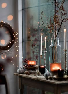 a table topped with candles next to a vase filled with flowers and other items on top of it