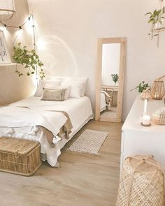 a bedroom with white walls and wood flooring is pictured in this image, there are wicker baskets on the side of the bed