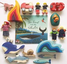 there are many toy animals and toys on the table together, including a book about whales