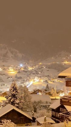 the snow covered mountains are lit up with lights in the distance and houses on either side