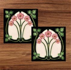 two coasters with pink flowers on them sitting on a wooden table next to each other