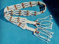 two white crocheted necklaces with brown beads on blue background, closeup