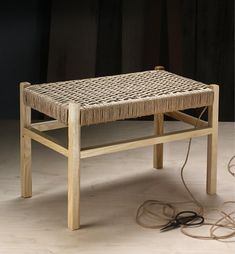 a wicker table sitting on top of a hard wood floor next to a power cord