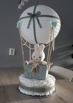 a stuffed bunny in a basket on top of a cake with a balloon attached to it