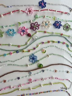 a bunch of different colored beads on a white table top with flowers and pearls attached to them