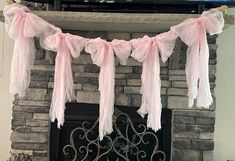 the fireplace is decorated with pink ribbon and streamers