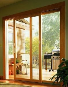 an open patio door leading to a deck with a bbq grill in the background