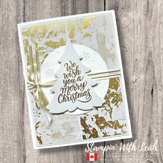 a white and gold christmas card on a wooden surface with the words we wish you a merry christmas