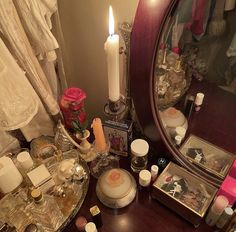 a vanity with candles, perfumes and other personal items on the table next to it