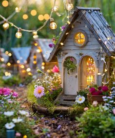 a small white house surrounded by flowers and lights