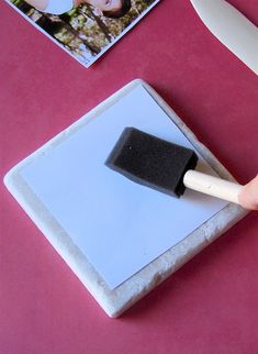 a person is using a brush to clean the tile on top of a pink table