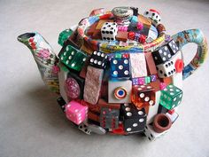 a teapot made out of dices and other items on the floor with a white background